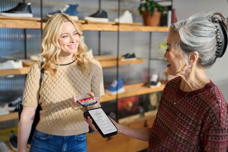 Woman making purchase with phone on credit card terminal at checkout